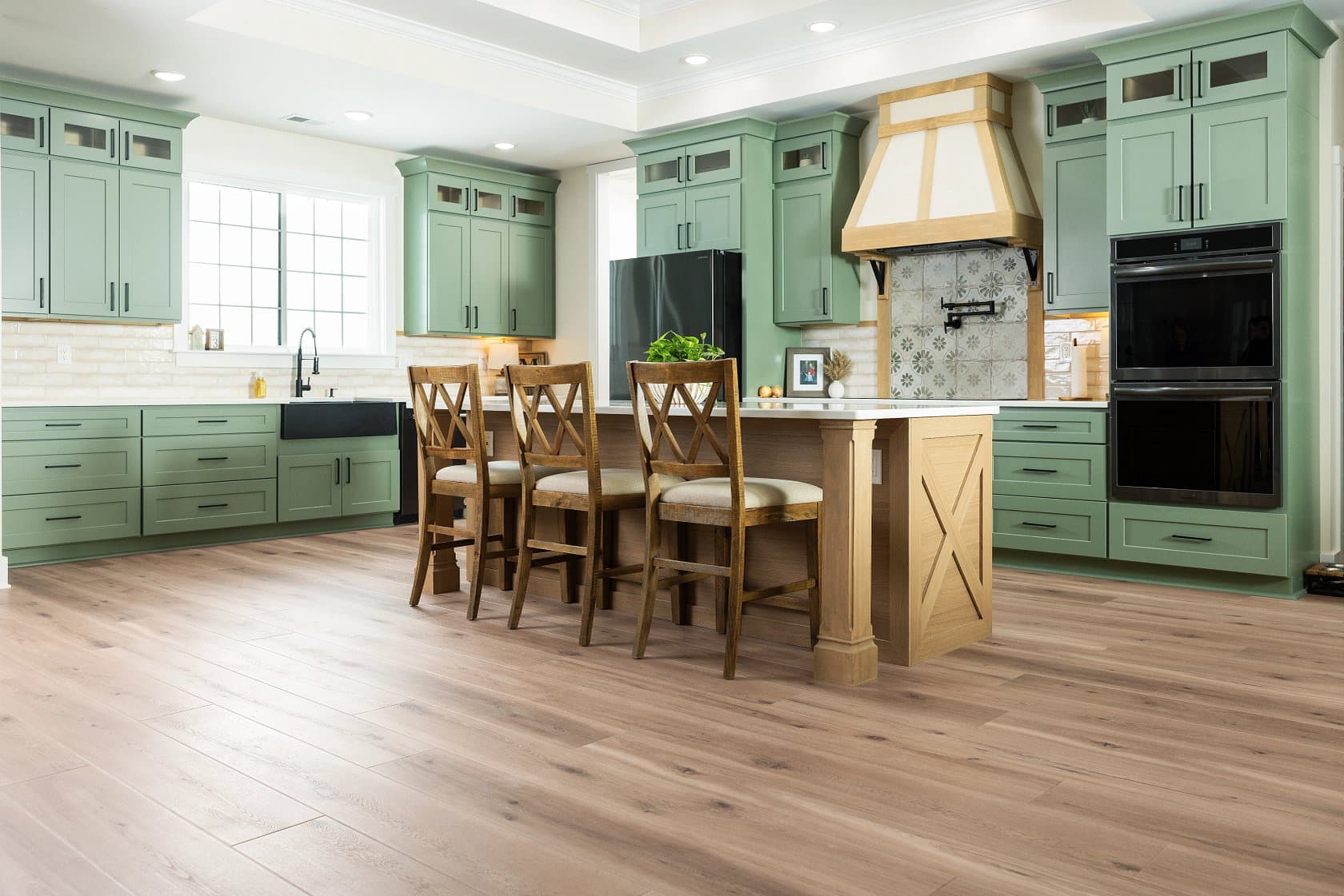 Sage-green kitchen with light oak-look luxury vinyl plank flooring in a Pine Ridge home, Naples