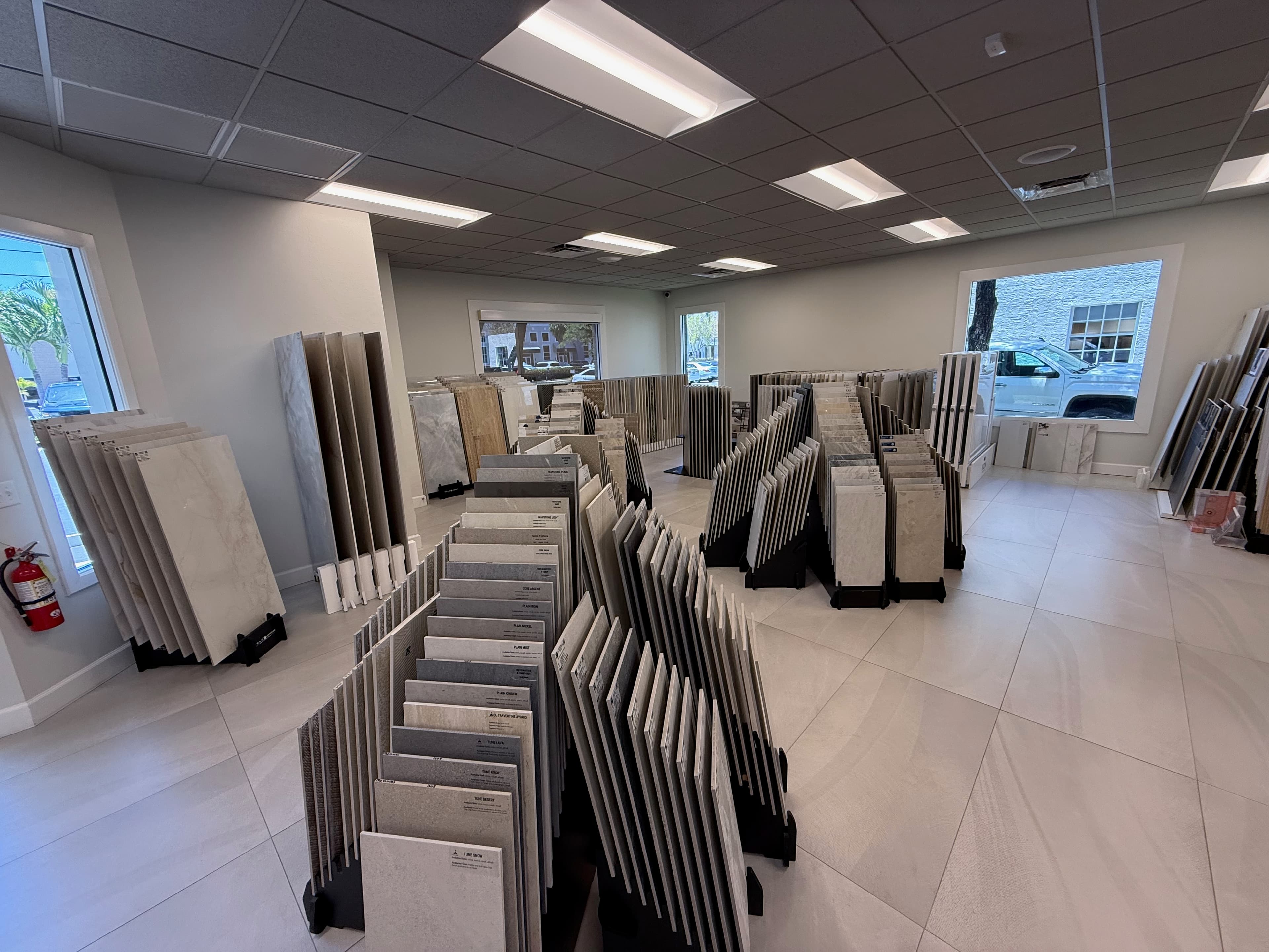 Full-height porcelain sheets standing upright on the racks in the ProFloors Naples showroom, with sample boards behind them