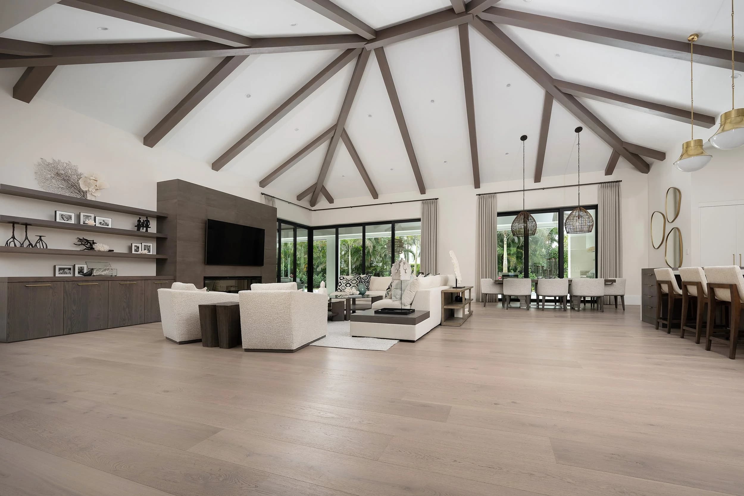 A vaulted, beamed Naples great room with wide-plank European white oak running wall to wall through the living and dining space