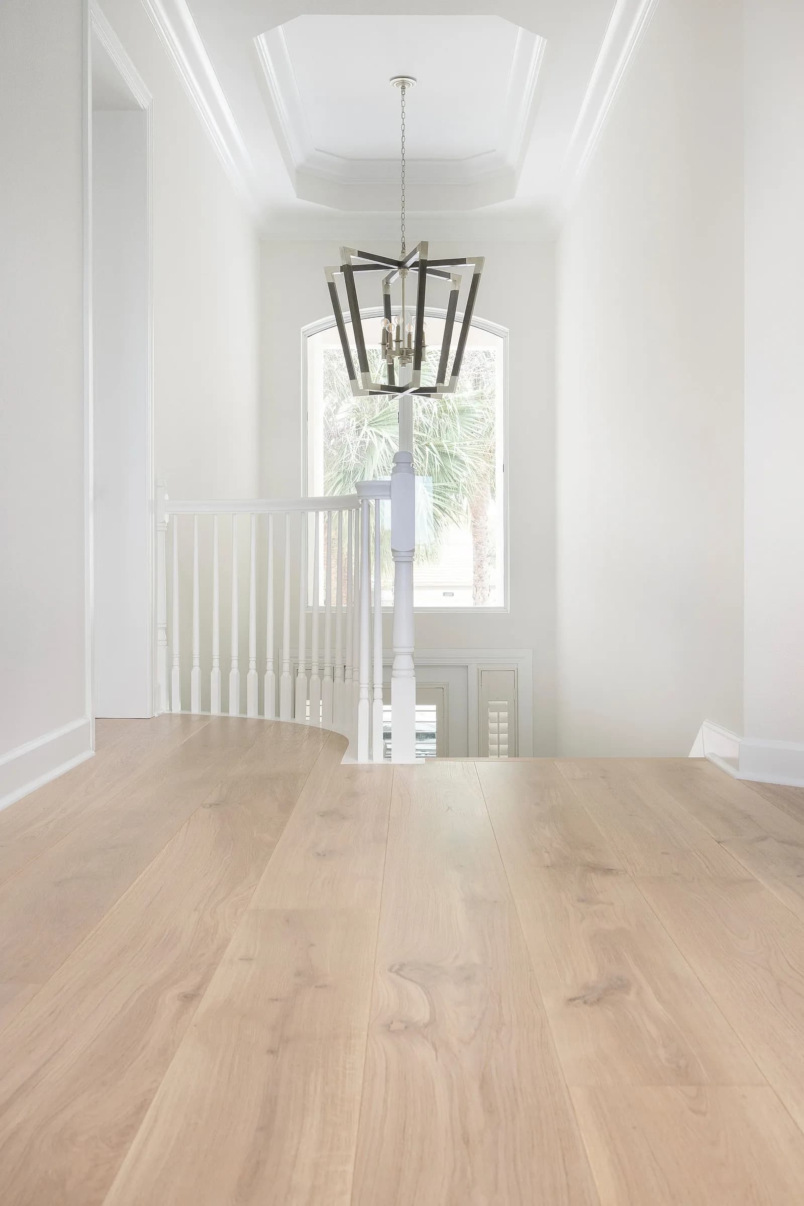 Entry & stair. A curved stair in a soaring, bright foyer.