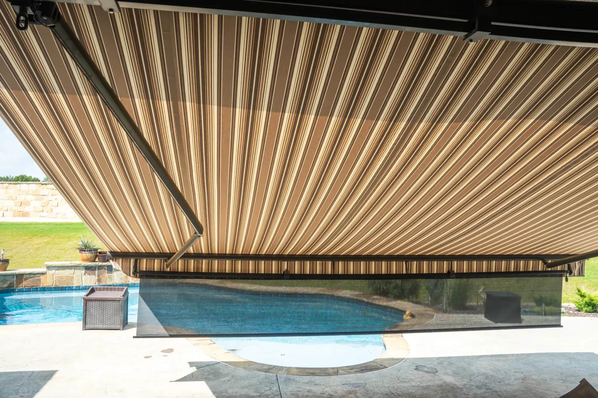 Retractable awning with a front drop screen shading a poolside seating area