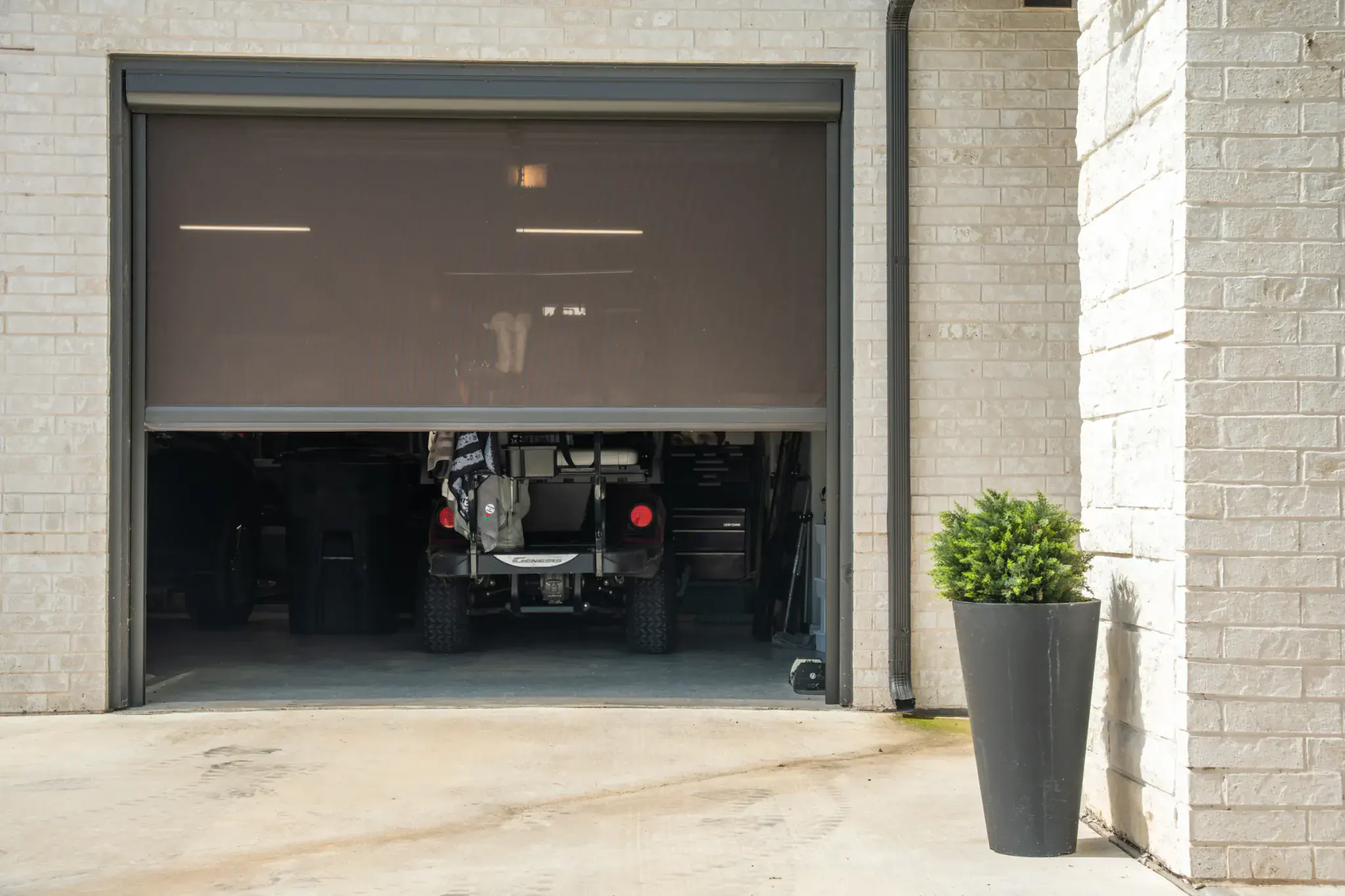 Motorized insect screen lowered across a residential golf cart garage opening
