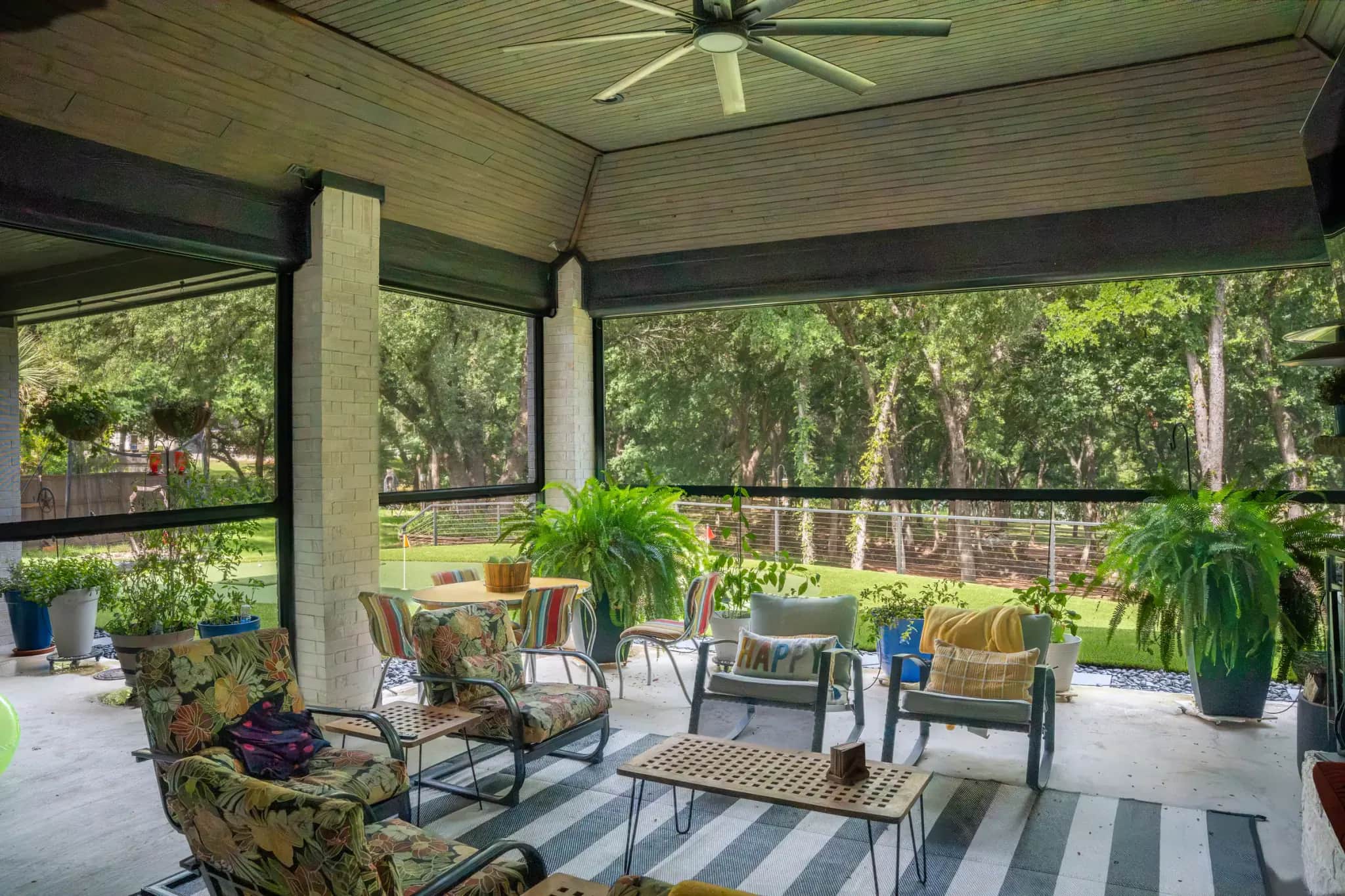 Motorized insect screens surrounding a furnished porch beside a putting green