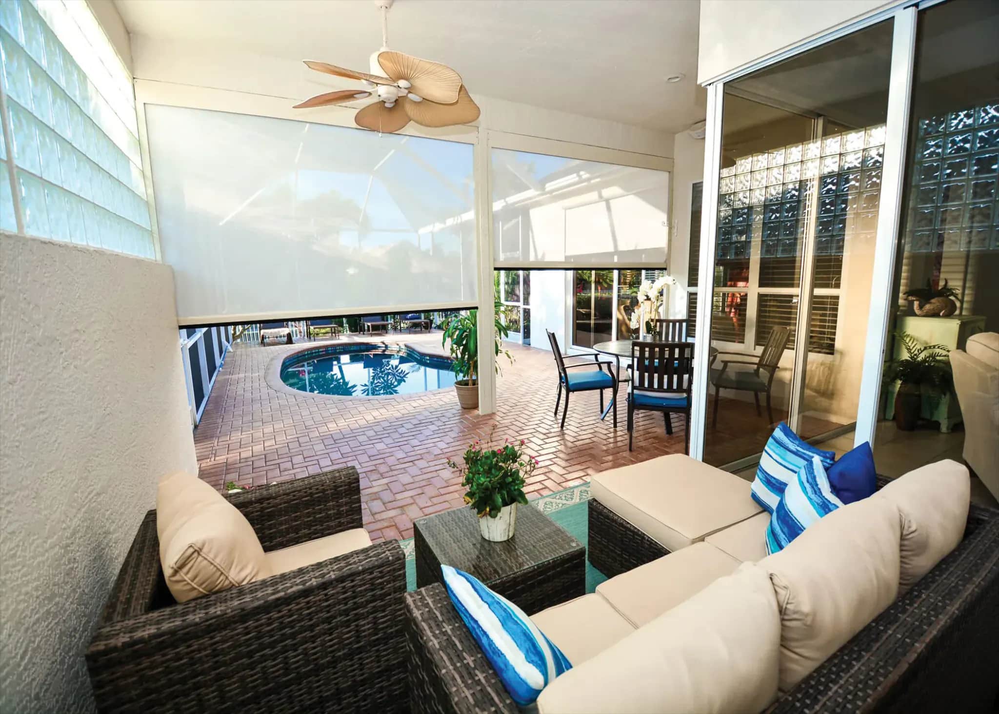 Motorized solar screen lowering across a furnished pool lanai