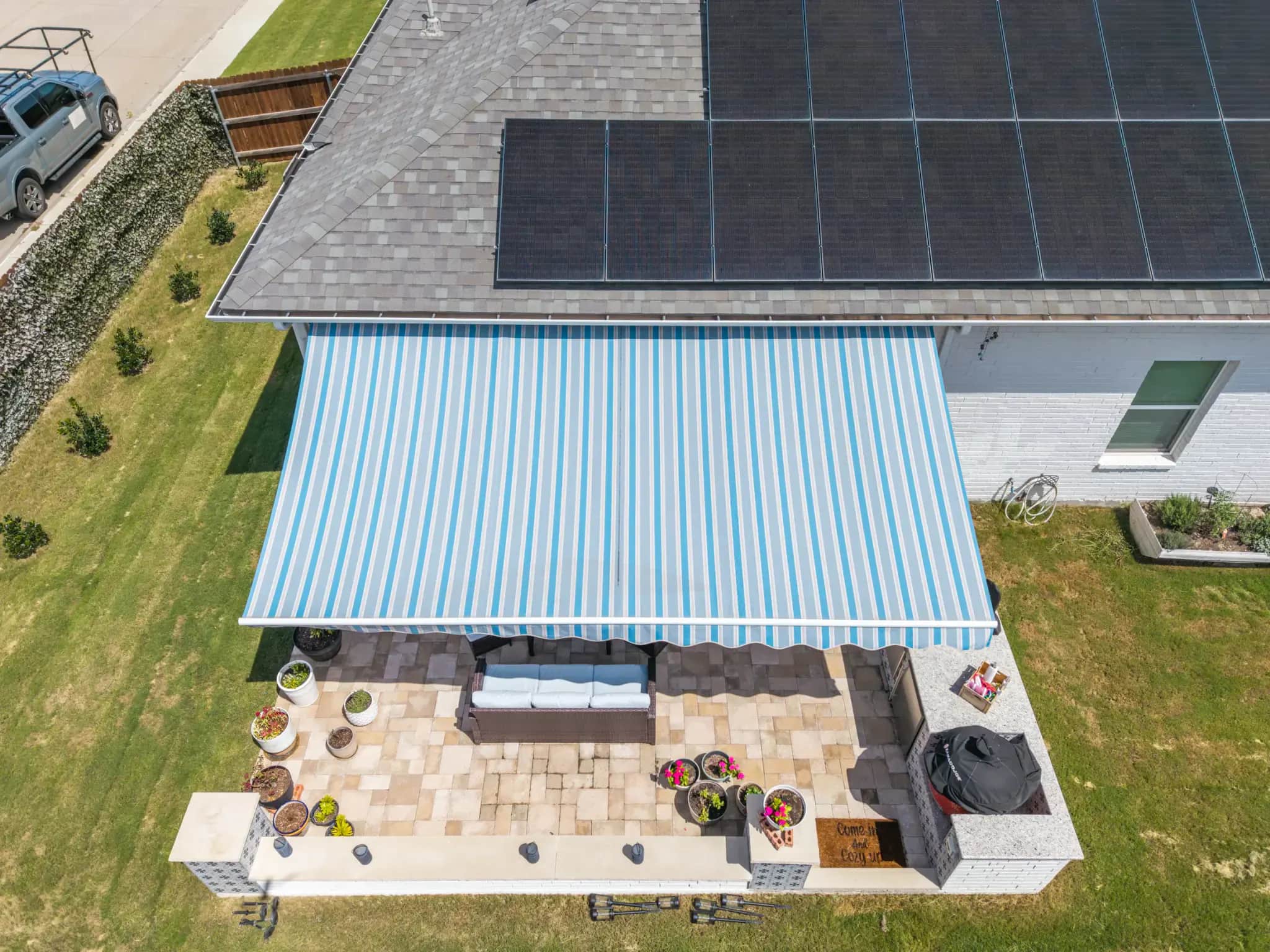 Retractable striped awning extended over a residential outdoor kitchen and patio
