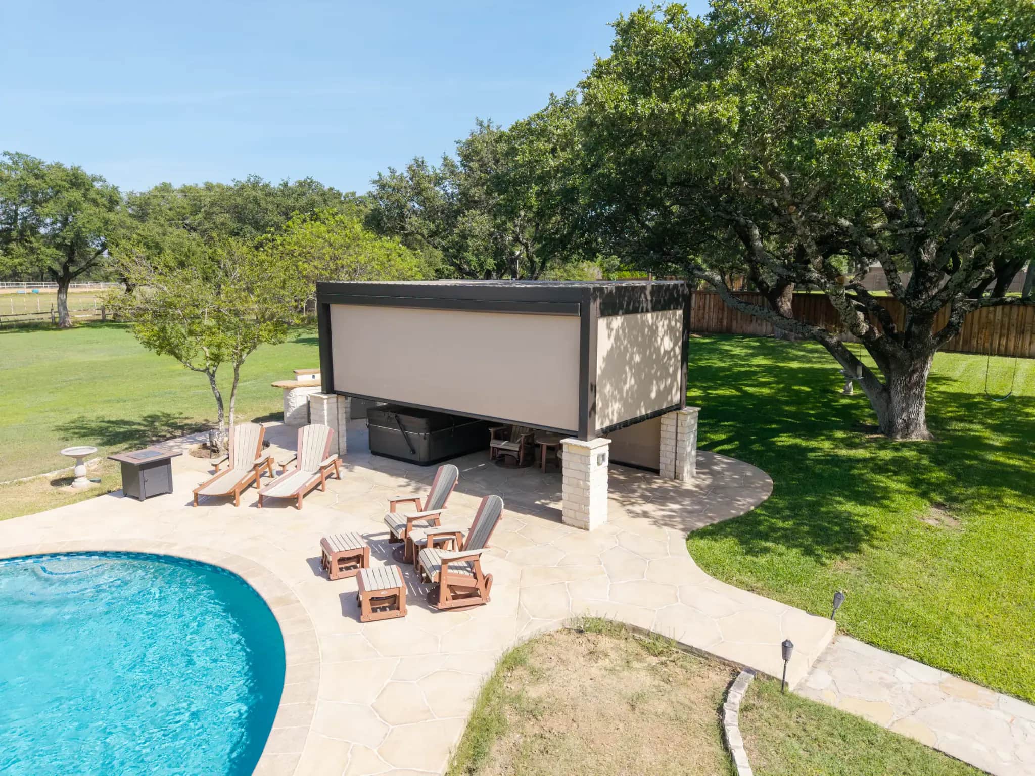 Motorized screens enclosing a freestanding pergola beside a swimming pool